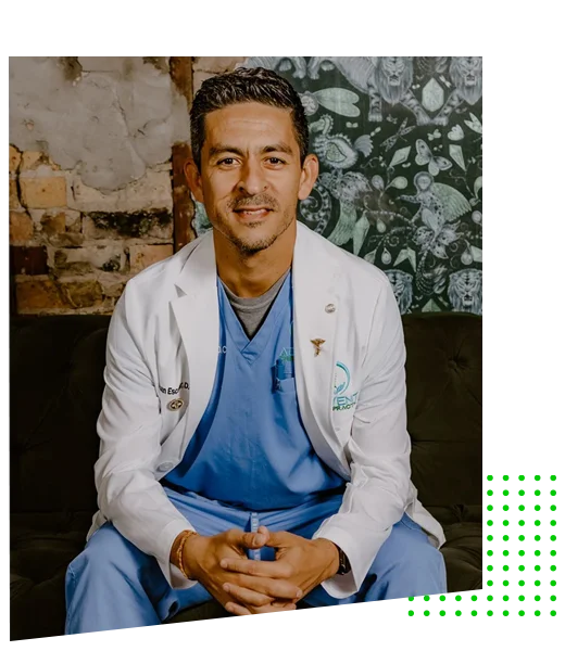 Chiropractor Kissimmee FL Juan Escobar HP About Dr. Juan Escobar posing for a professional photo in scrubs and white coat